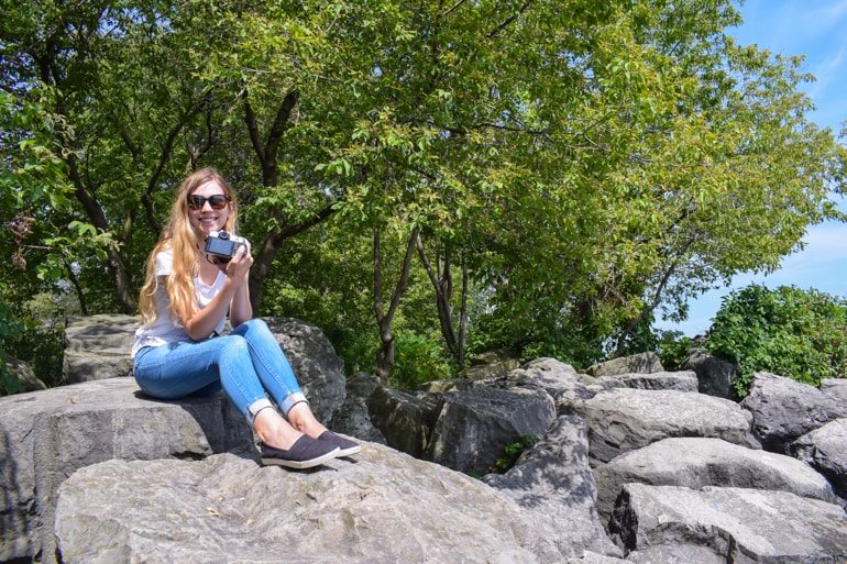 girl sitting in rocks with shoreline travelling to canada for the first time