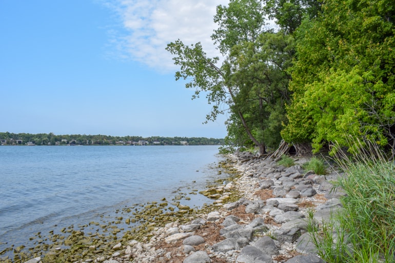 rocky shoreline with green trees and blue lake travelling to ontario for the first time