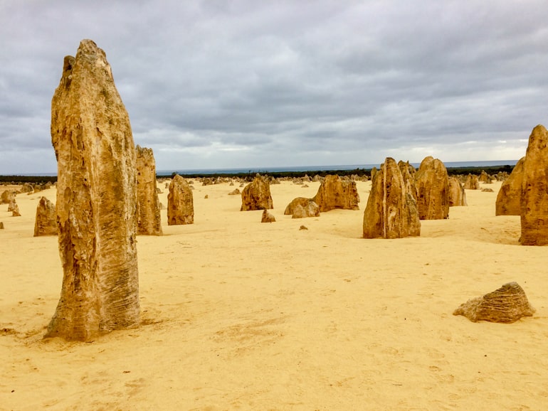 Große Steine auf sandigem Boden mit grauem Himmel pinnacles of nambung australien