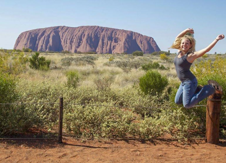 Frau springt vor Uluru Rock in Australien
