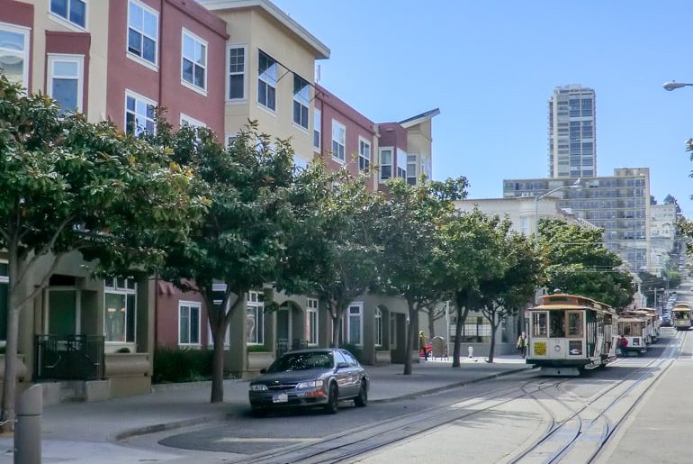 cable cars on street with green trees top 10 things to do in san francisco