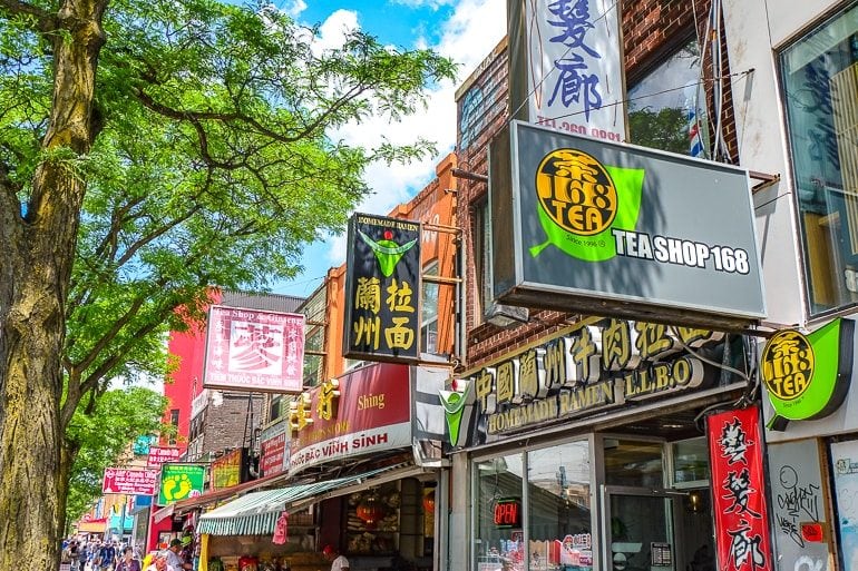 Bunte Schilder mit chinesischen Schriftzeichen und grünen Bäumen in Toronto Chinatown