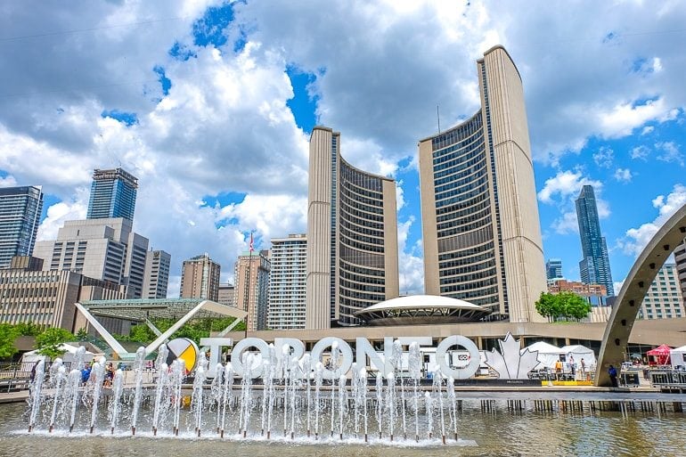 fountain in front of large white letters and curved building city hall toronto nathan phillips square
