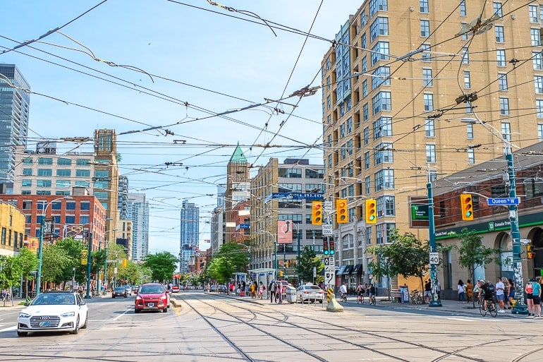busy city intersection with cars driving and streetcar cables above.