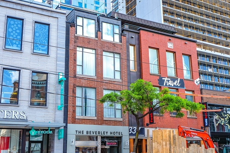 small hotel among brick buildings with shop fronts in toronto on queen street