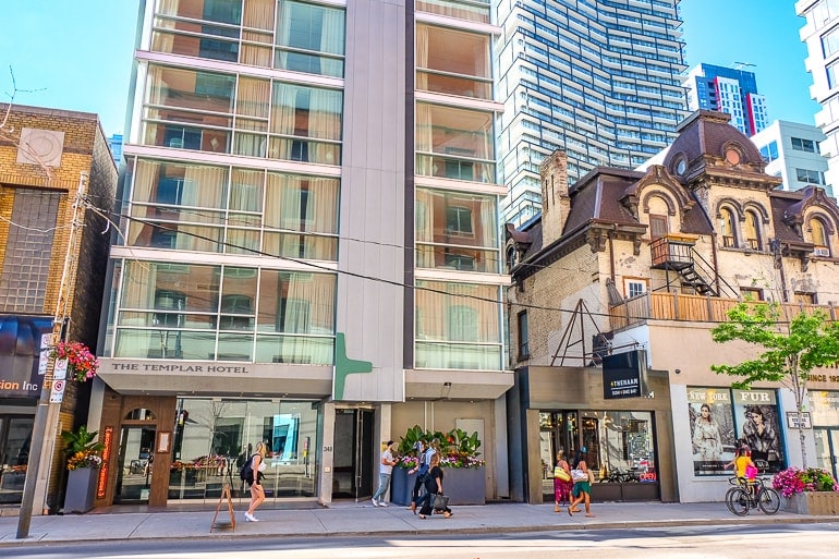 Schmales Hotel aus Glas mit Menschen auf dem Bürgersteig im Vordergrund in Toronto