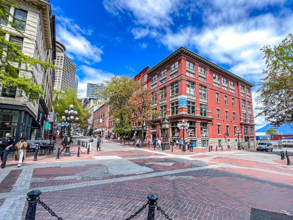 red brick building on street corner in historical area gastown of vancouver with people walking around.