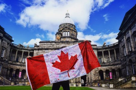 canada flag with old building and blue sky working holiday visa canada