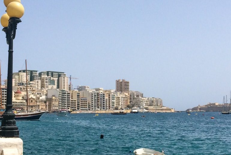 blue harbour boardwalk with buildings malta sightseeing