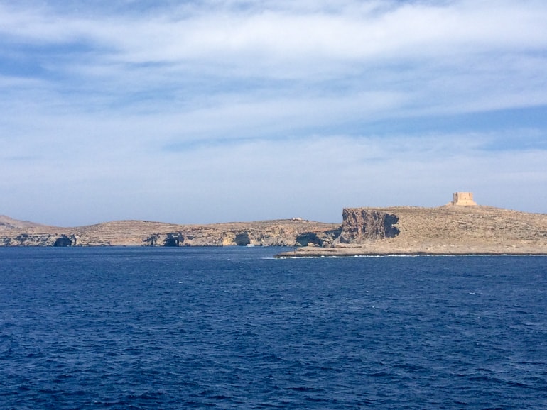 Sandsteinfarbener Turm auf Insel mit blauem Meer Malta Sehenswürdigkeiten
