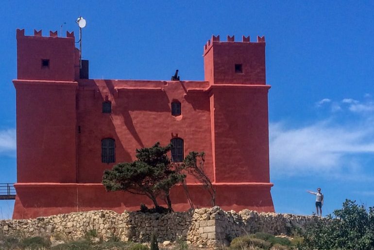 red castle tower with person beside malta sightseeing 