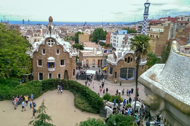 uniquely designed buildings at park guell entrance with city below