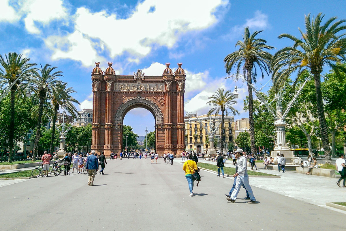 Roter Torbogen mit Menschen im Vordergrund Arc de Triomf Barcelona.