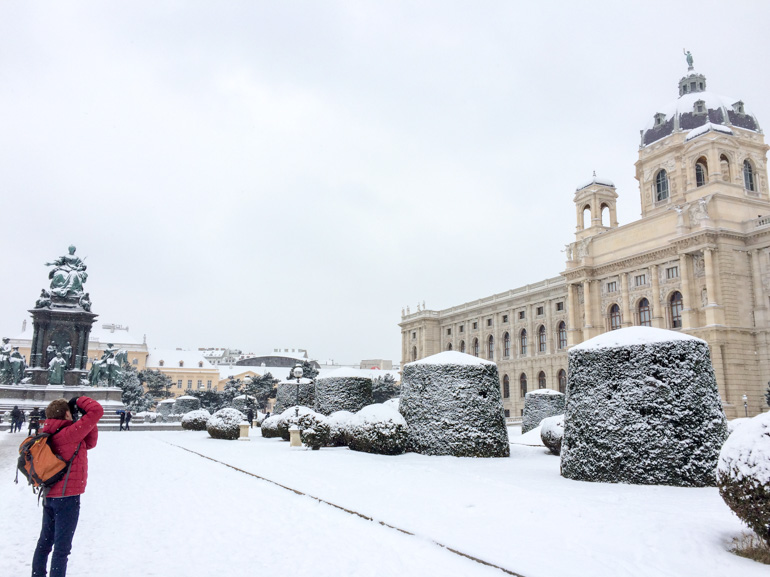 Mann in roter Jacke macht Foto von verschneitem Wien Österreich