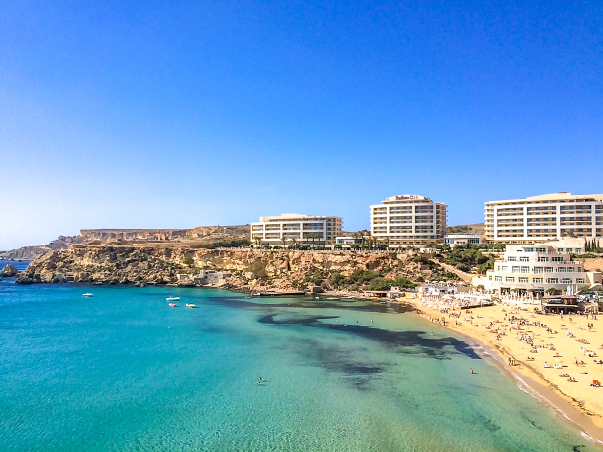 Sandstrand, blaues Meer und Resort-Hotels an der Steilküste in Mellieha, Malta