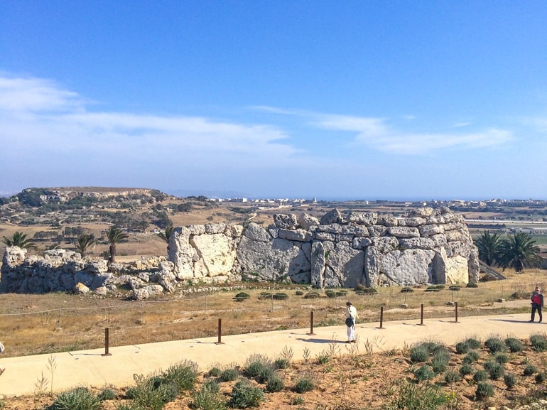Steintempel im Feld mit Menschen, die den Steinweg in Xaghra Gozo entlanggehen 
