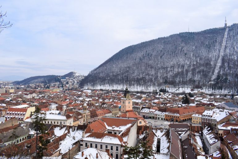 old town buildings with snow and mountain must see places in europe in winter brasov romania