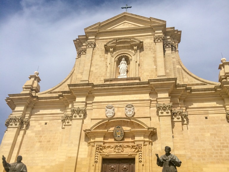 stone church front with statues and blue sky things to do in gozo