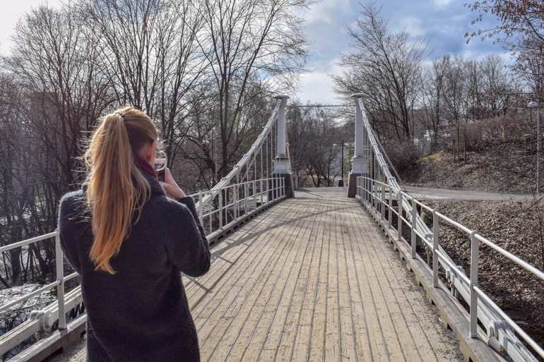 girl taking photo of wood suspension bridge things to do in oslo norway