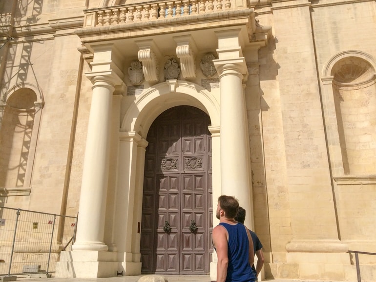 brown door and stone pillars with men gazing things to do in valletta