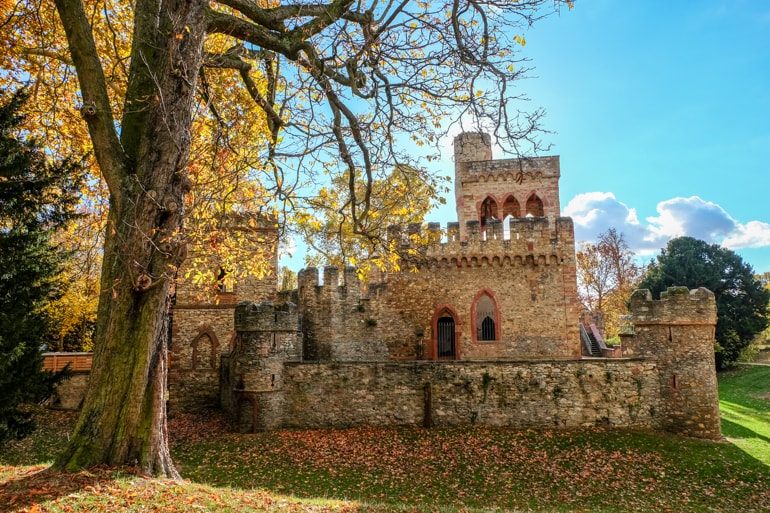 small stone castle with blue sky and autumn tree in front things to do in wiesbaden