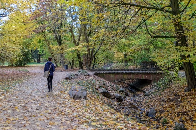 Frau mit Tasche läuft in grünem Park neben Brücke Wiesbaden