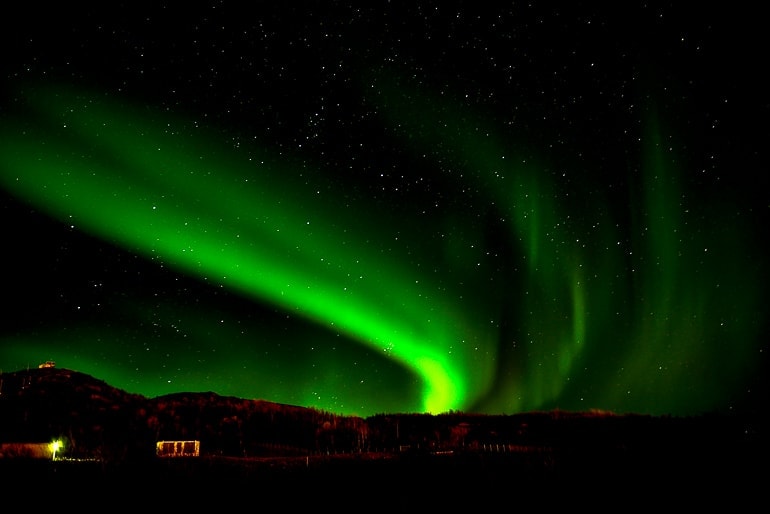 Grüne Nordlichter an dunklem Himmel in Schweden