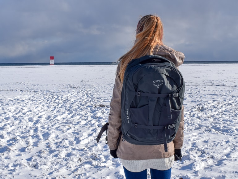 girl with backpack standing on snowy field trips to see the northern lights packing tips