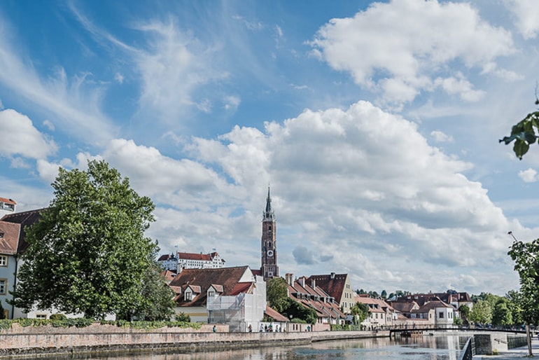 Wasser und blauer Himmel mit Häusern und Kirchturm im Hintergrund Landshut schöne Städte Deutschland