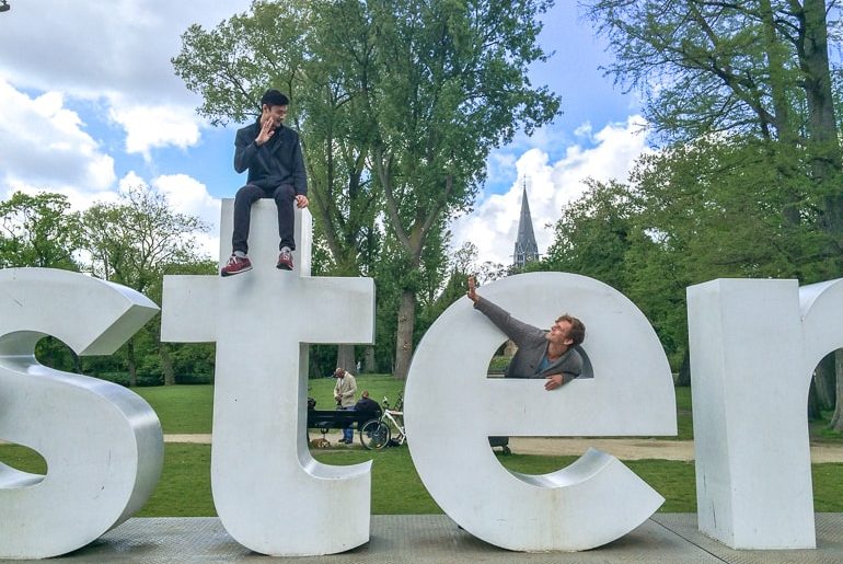 two guys waving from large white letters european hostels amsterdam netherlands