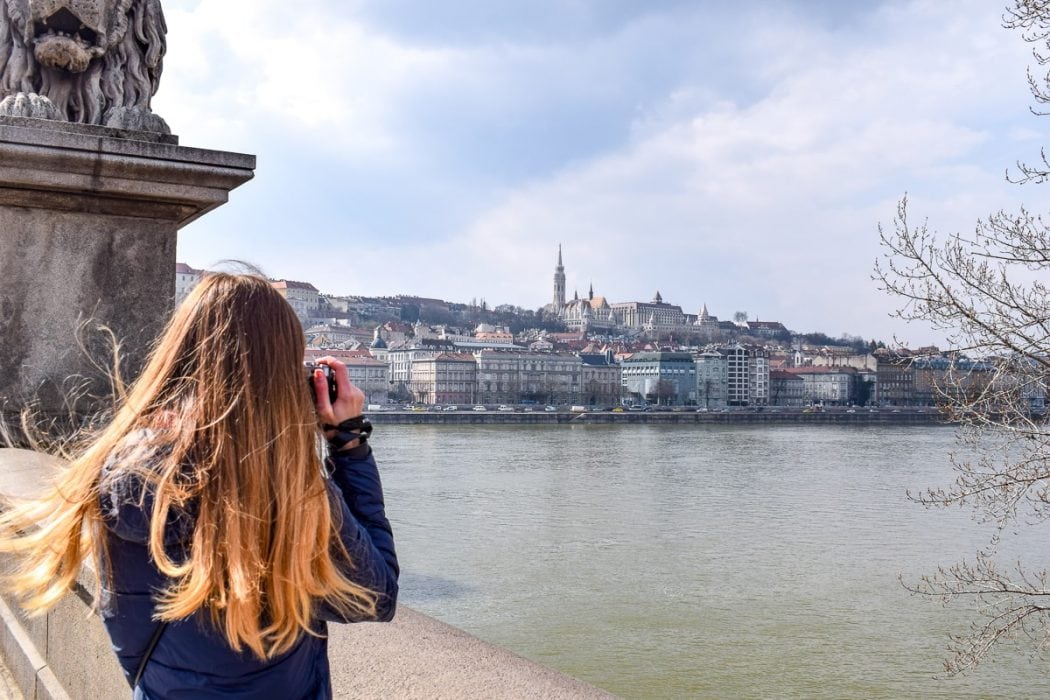 Blonde Frau mit Kamera macht Foto von Schloss und Fluss Budapest Ungarn
