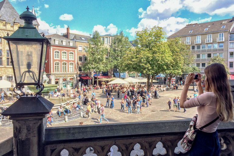 Frau macht Foto vom Aachener Marktplatz Hostels Deutschland