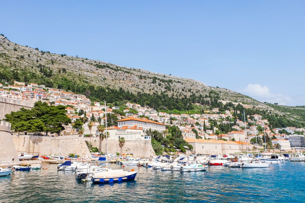 Boote am Hafen im blauen Wasser mit Villen am Hang dahinter in Dubrovnik