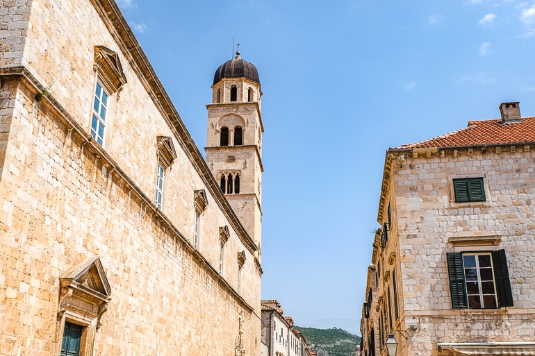Hoher Steinturm und Gebäude aus Sandstein in der Altstadt Dubrovniks mit blauem Himmel dahinter