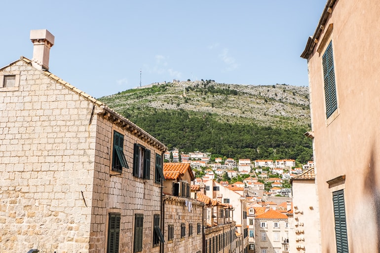 Altstadtgebäude aus Sandstein mit grünem Hügel in der Ferne in Dubrovnik