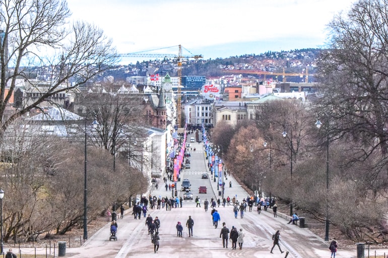 Menschen, die eine lange, breite mit Bäumen gesäumte Straße entlanggehen in Oslo.