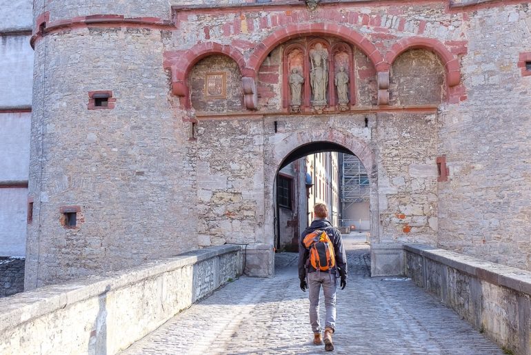 boy with backpack walking into old castle travelling to europe for the first time