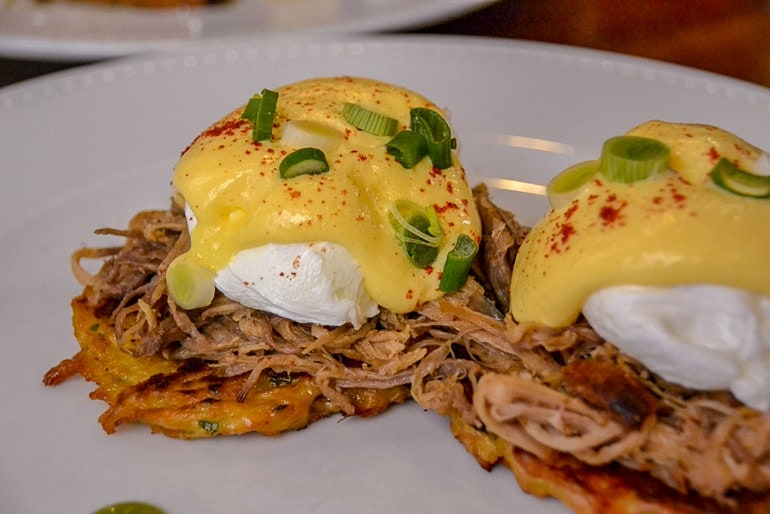 pulled pork eggs benedict on white plate one day in budapest