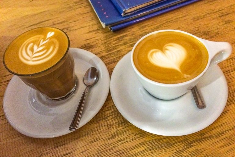 two coffees with latte heart art on wood table one day in budapest