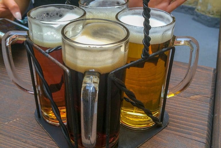four beer in pint glasses on table one day in prague