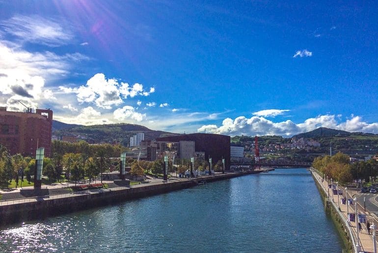 river splitting a city centre with blue sky things to do in bilbao spain