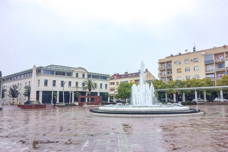 Brunnen auf offenem Platz mit Gebäuden außenrum Podgorical Motenegro günstige Städtereisen