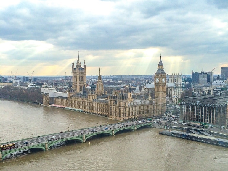 westminster palace and big ben clock tower beside and thames river in front seen from above.