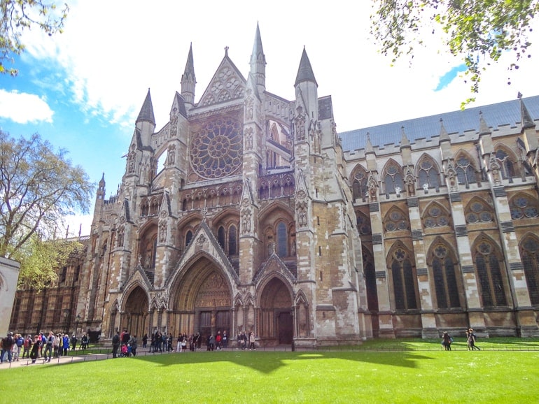 historic church entrance with green lawn in front at westminster abbey in london.