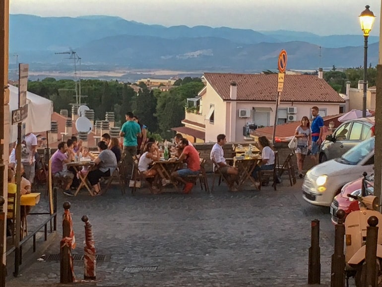 people sitting at tables at cafe with scenic view behind frascati