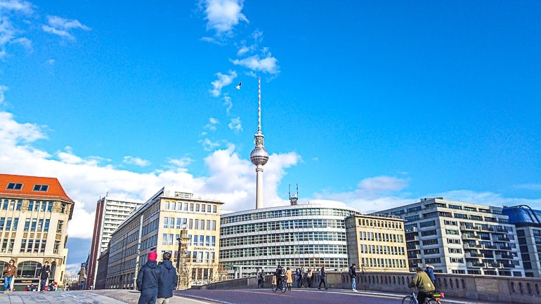 tower over city buildings with blue sky behind one day in berlin