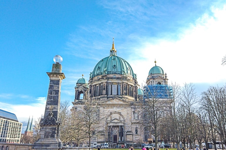 church with green domes and blue sky behind berlin dom