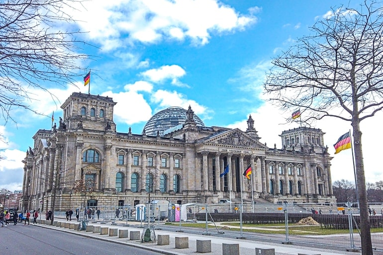 large parliament building with german flags and glass dome on top reichstag one day in berlin