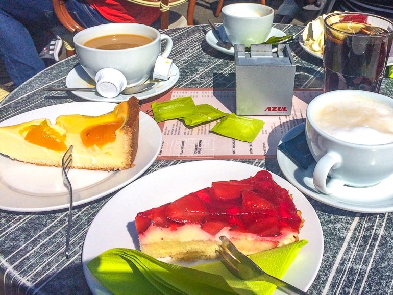 Kaffee und Kuchenstück auf Teller im Sonnenschein
