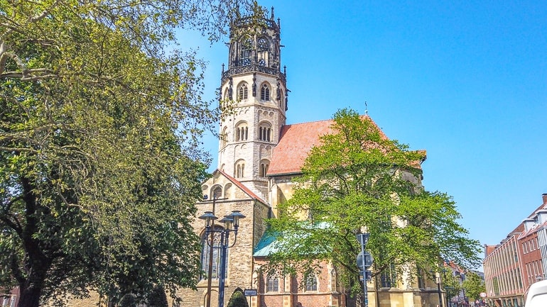 Kirche mit Türmen durch grüne Bäume Sehenswürdigkeiten Münster